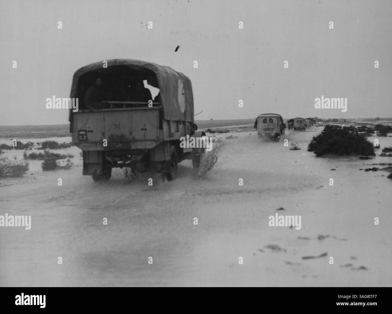 Konvois fahren entlang einer überfluteten Straße in der Nähe von Fukka auf dem Weg nach Mersa Matruh. Februar 1943. (Foto vom Department of Information, Commonwealth of Australia). Stockfoto