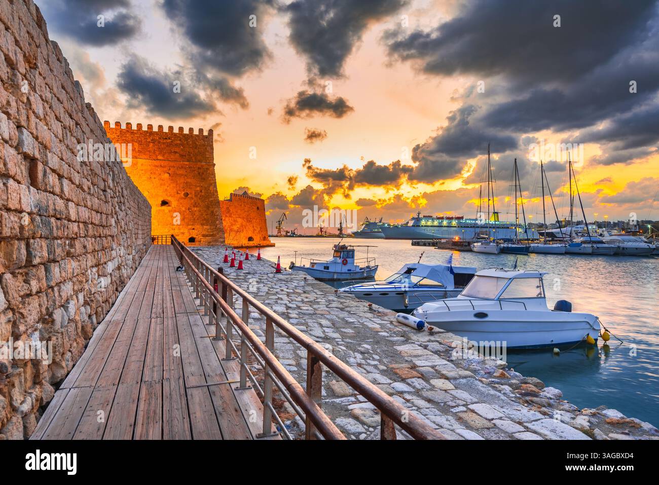 Heraklion, Griechenland. Alter Hafen mit Fischerbooten und Yachthafen während der dämmerlichen blauen Stunde, Insel Kreta. Boote haben die Bewegung im Vordergrund verschwommen. Stockfoto