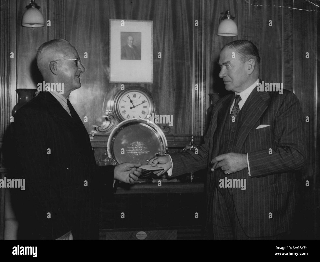 Angestellter geehrt – James Leo McGahey, erster Angestellter, der 50 Jahre bei Associated Newspapers Ltd. (Publishers of the Sun) arbeitet und jetzt pensioniert ist, erhält von Sir John Butters. Vorstandsvorsitzender, ein silberner Kaffeeservice, eine goldene Armbanduhr und zwei Kugelschreiber, Geschenke des Vorstands, diese Geschenke waren zusätzlich zu der Pensionierungszulage von 100 Wochen Gehalt des Unternehmens. McGahey trat im Februar 1901 im Alter von 15 Jahren der Organisation bei. Mai 1951. Stockfoto