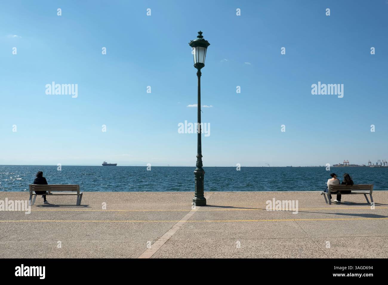 Menschen, die sich auf der Nea Paralia - Strandpromenade in Thessaloniki, Griechenland, entspannen. Stockfoto