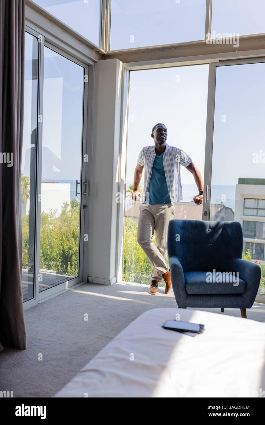 Entspannen auf dem Balkon, Mann genießt Morgensonne mit Smartphone auf dem Bett. Entspannung, Technologie, Lifestyle, Urban, Freizeit, Komfort Stockfoto