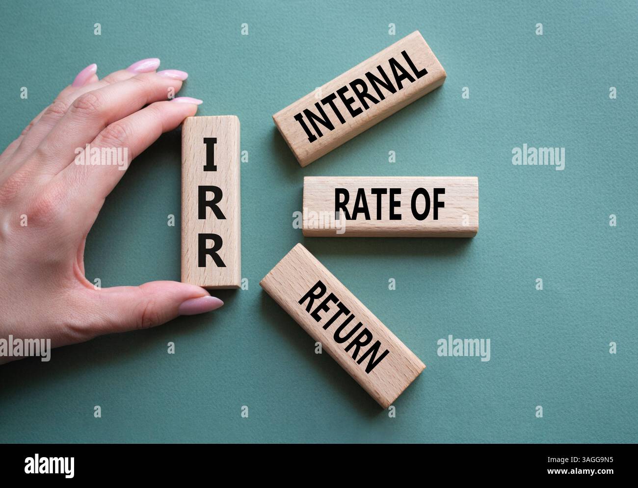 IRR – Symbol für interne Rückkehrrate. Konzeptwort IRR auf Holzwürfeln. Geschäftsmann Hand. Wunderschöner graugrüner Hintergrund. Business und IRR-Konzept. C Stockfoto
