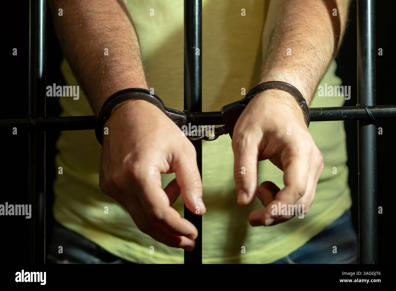 Inhaftierung - eine männliche Figur mit Handschellen hinter Metallstäben Stockfoto