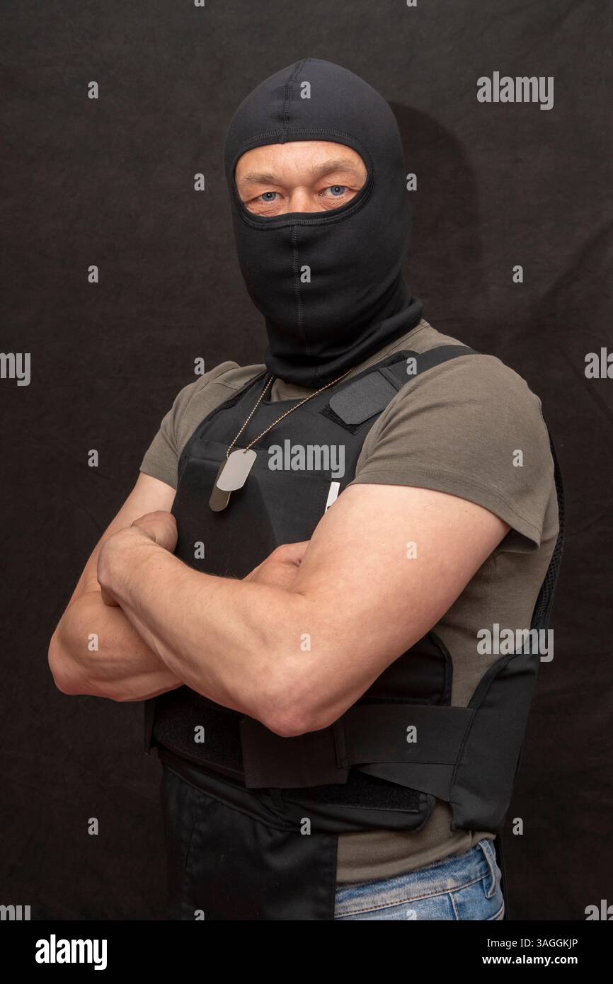 Porträt eines muskulösen Militärs 45-50 Jahre alt in einer kugelsicheren Weste und Sturmhaube auf dunklem Hintergrund. Konzept: Freiwillige für Krieg, Krieg in der Ukraine Stockfoto