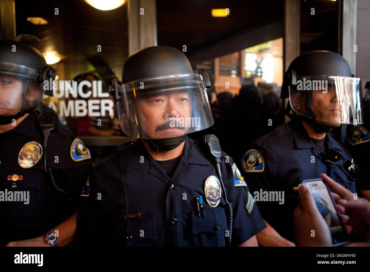 24. Juli 2012 - Anaheim, Kalifornien, USA - Polizeibeamte von Anaheim bewachen die Council Chambers am Dienstagnachmittag während eines Protests in der Großstadt gegen die von der Polizei betroffenen Erschießungen am Wochenende. Die Polizei wurde mit Aufruhr ausgerüstet und verteilte schließlich eine Menge wütender Demonstranten mit Gummigeschossen und Paintball-Kugeln während einer Straßenblockade später am Abend. Hunderte von Demonstranten versammelten sich am Dienstag, den 24. Juli 2012, im Rathaus von Anaheim, nachdem zwei umstrittene polizeibezogene Erschießungen zwei, 25-jährige Manuel Diaz und den 21-jährigen Joel Mathew Acevedo getötet hatten Stockfoto