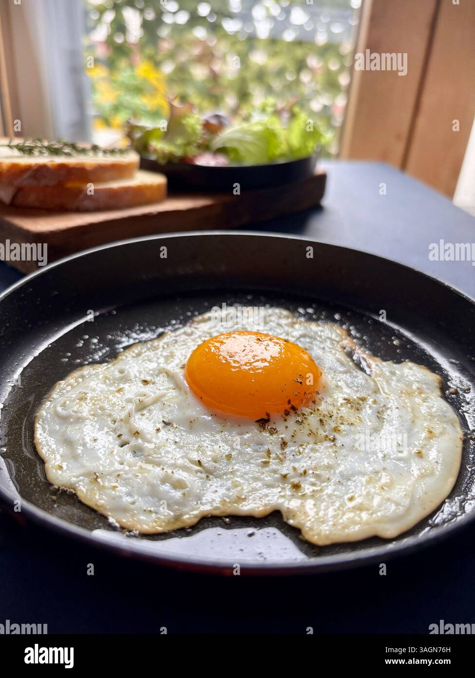 Ein einzelnes Spiegelei in einer Pfanne, serviert mit Gemüse und Brot auf dem Tisch. Gesundes Lebensmittelkonzept. Nahaufnahme. Stockfoto