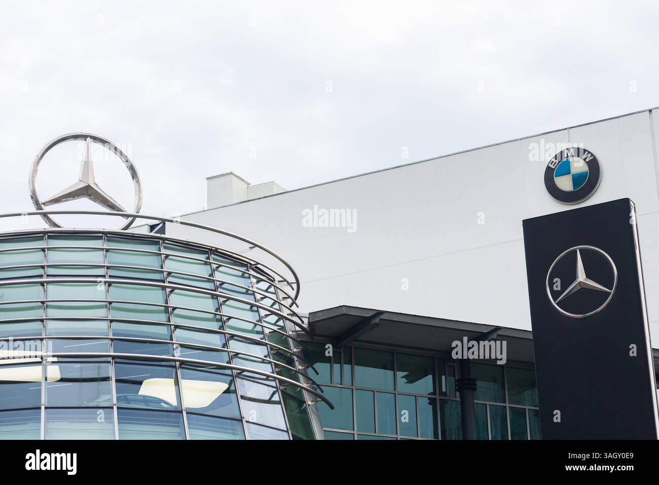 Silberner Pfeil mit Mercedes- und BMW-Logo und Beschilderung, um den Käufer zum Kauf teurer Luxusfahrzeuge zu locken. Showroom in Singapur. Stockfoto
