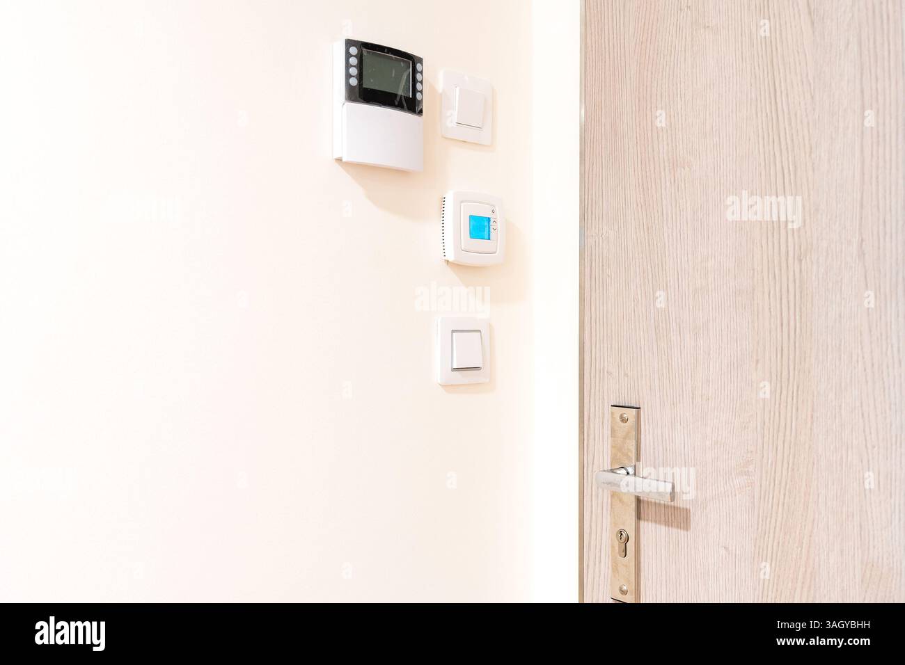 Smart-Home-Bedienfeld und Thermostat an weißer Wand in modernem Innenraum Stockfoto
