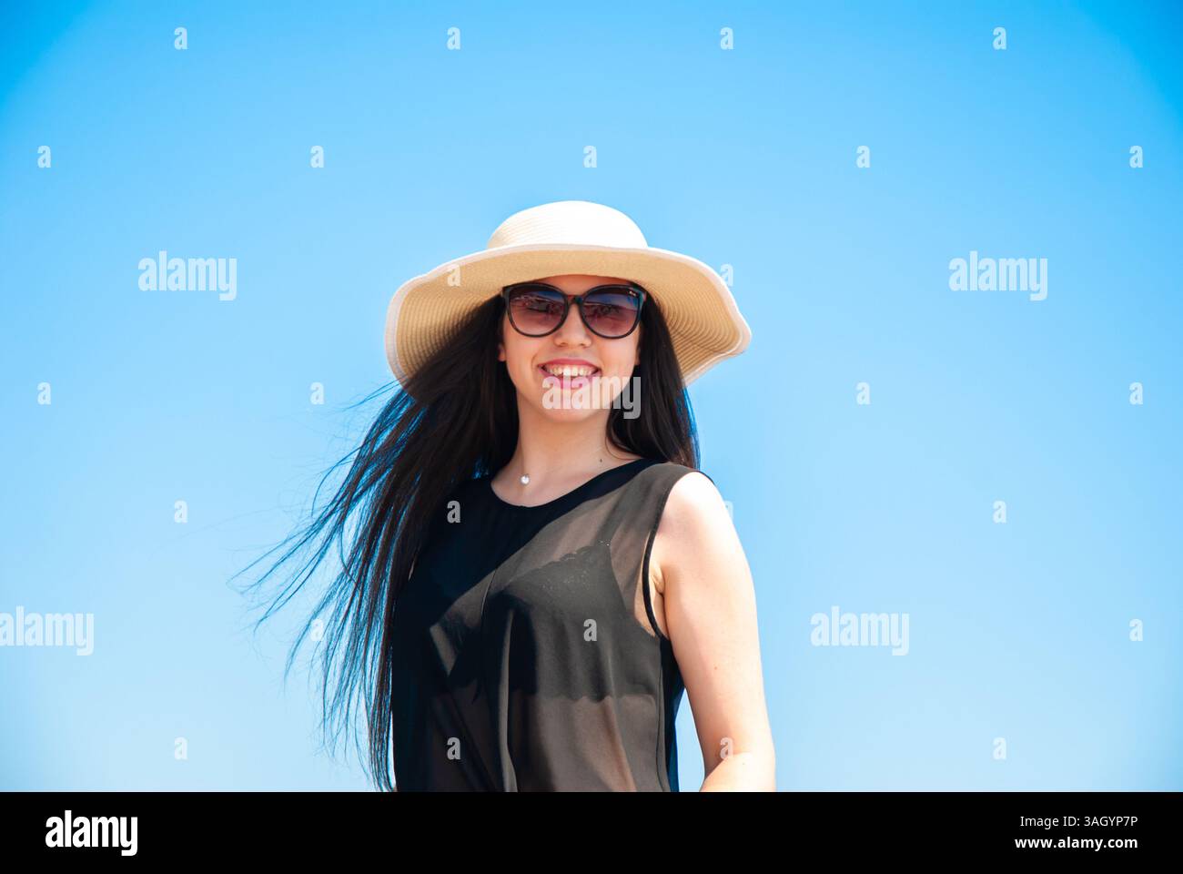 Lächelnde Frau in Sonnenhut und Sonnenbrille, die einen sonnigen Tag im Freien genießt. Frohe Sommertage, Reise- und Urlaubskonzept. Stockfoto