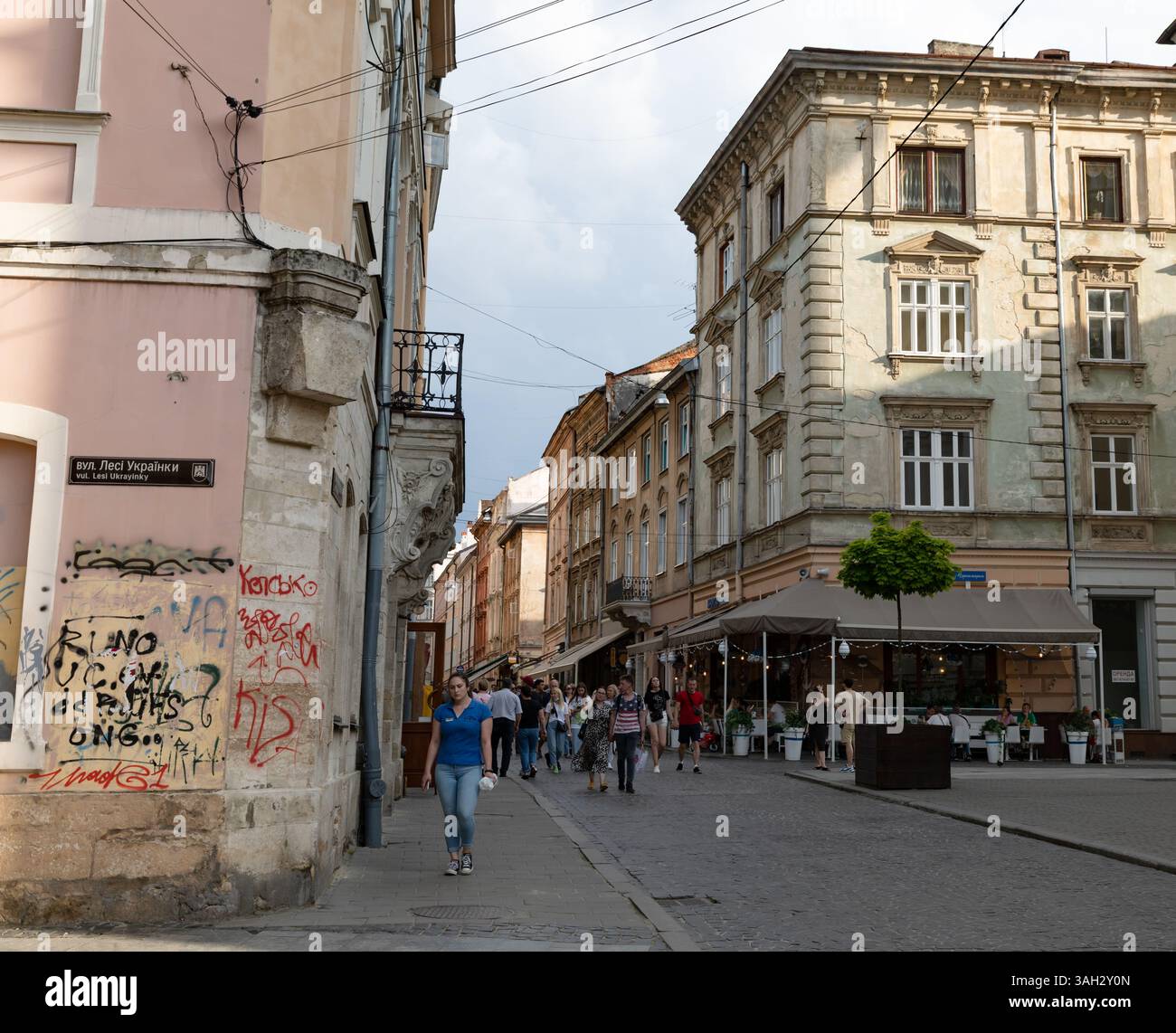 LEMBERG, UKRAINE - 20. Juni 2021: Die Menschen schlendern durch die kopfsteingepflasterten Straßen des historischen Viertels, bewundern klassische Architektur und genießen die Cafés im Freien in der lebhaften Atmosphäre. Stockfoto