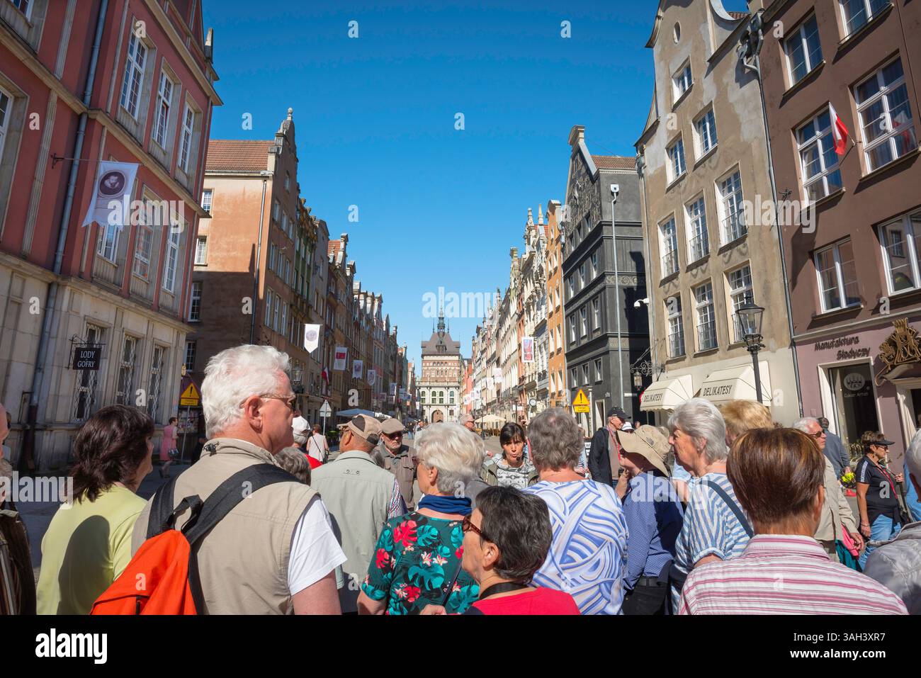 Stadt der Tourismusgruppe, Blick auf eine Reisegruppe, die einem Reiseleiter lauscht, wie er in Dlugi Targ steht, der Hauptdurchgangsstraße in der Altstadt von Danzig, Polen Stockfoto