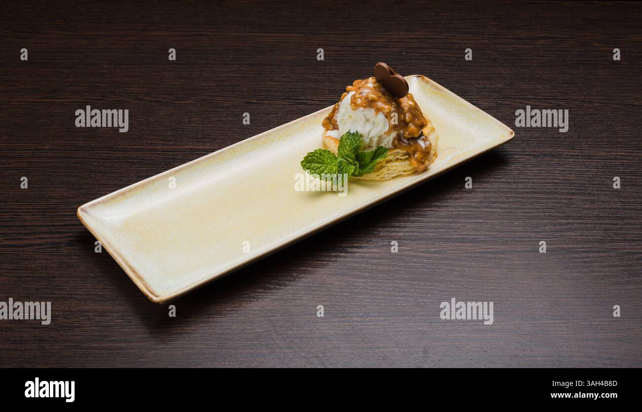 Dessert mit Blätterteig und Eis mit Karamell auf einem Teller Stockfoto