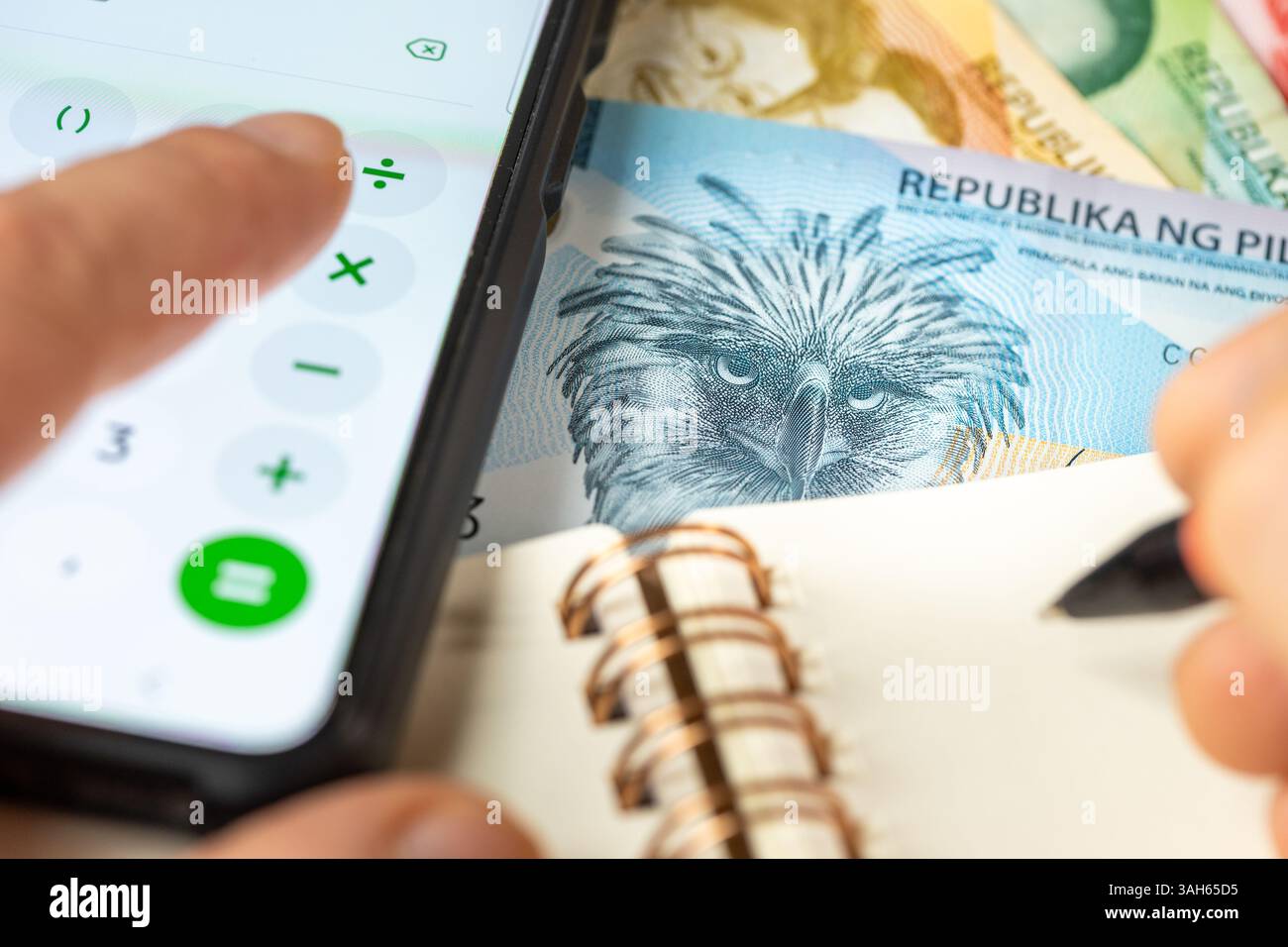 Philippinisches Geld. Zählen auf Smartphone-Rechner, PHP-Symbol, Notizen im Notebook. Finanzielle Abwicklung, Haushaltsbudget, Steuern, philippinische Währung Stockfoto