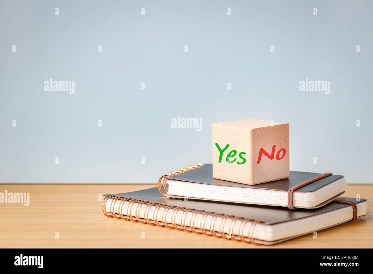 Die Worte "Ja" und "Nein" auf einem Holzwürfel, der auf Geschäftsnotizbüchern liegt. Kopierbereich Stockfoto