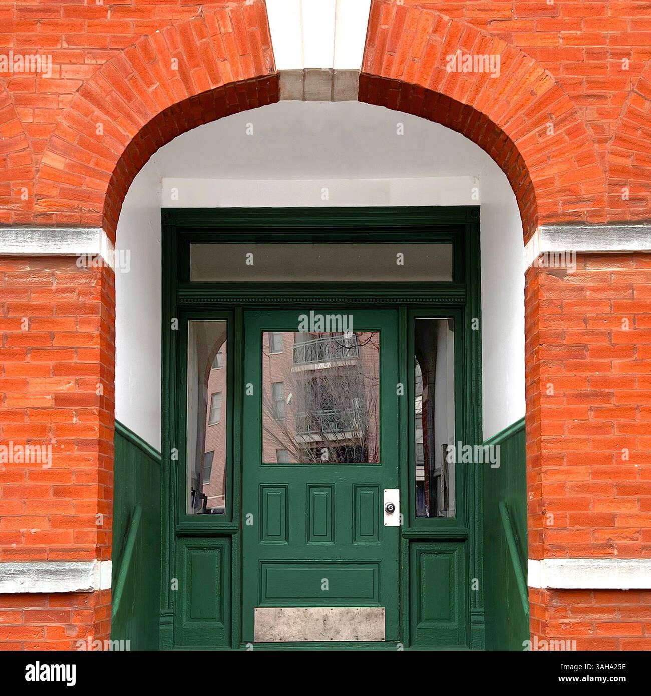 Klassischer grüner Eingang, der von roten Backsteinen und Steinbögen in Chicago eingerahmt wird, verbindet kräftigen Farbkontrast mit historischem architektonischem Charme - Smartphone-aufgenommenes Stockfoto