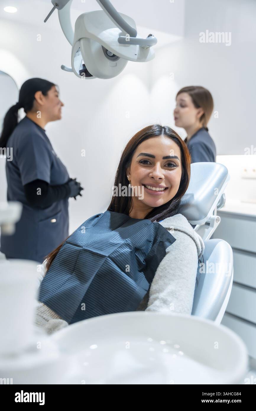 Die Patientin lächelt während eines Arztgesprächs auf einem Zahnarztstuhl Stockfoto