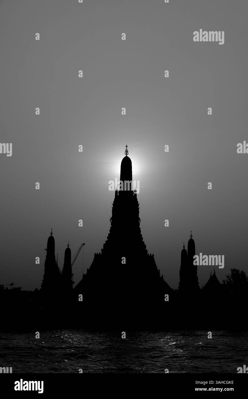 Die Sonne geht direkt hinter dem zentralen Turm des Wat Arun in Schwarzweiß unter Stockfoto