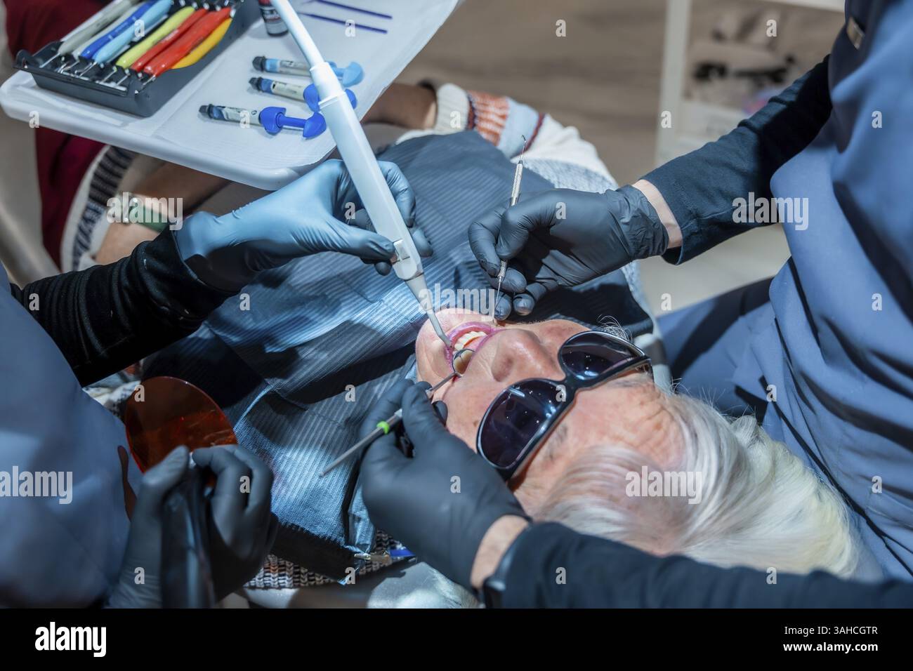 Zahnarztpraxen mit Spezialwerkzeugen führen in einer modernen Zahnklinik eine Zahnaufhellung bei einer älteren Patientin durch Stockfoto