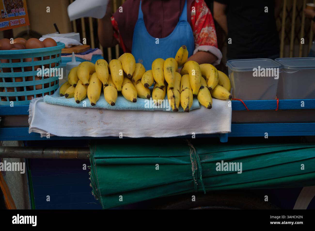 Frische Bananen, die ordentlich auf dem Wagen eines Straßenverkäufers liegen Stockfoto