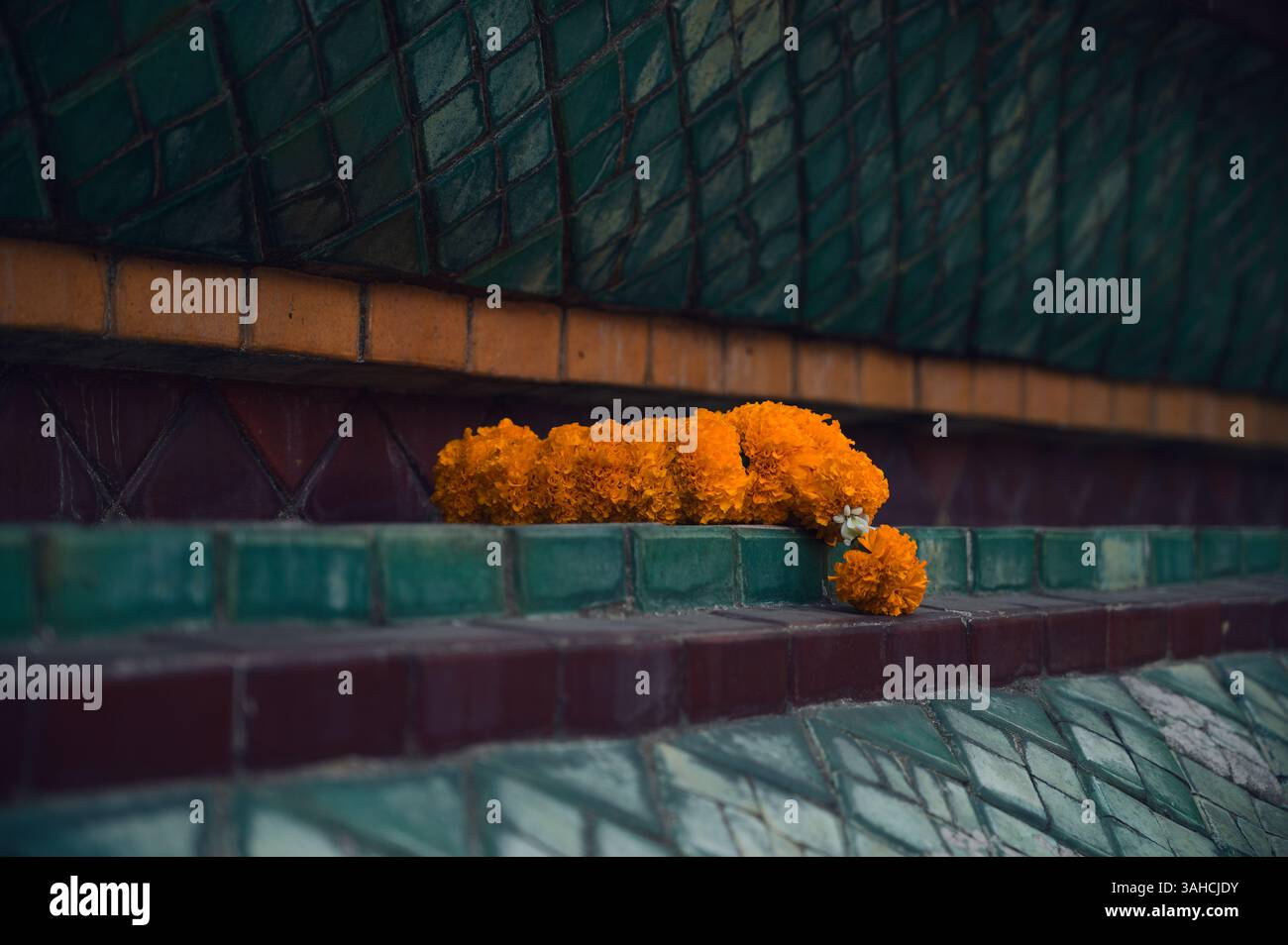 Eine einsame Ringelblumengirlande ruht leise auf den Tempelfliesen des Wat Pho Stockfoto