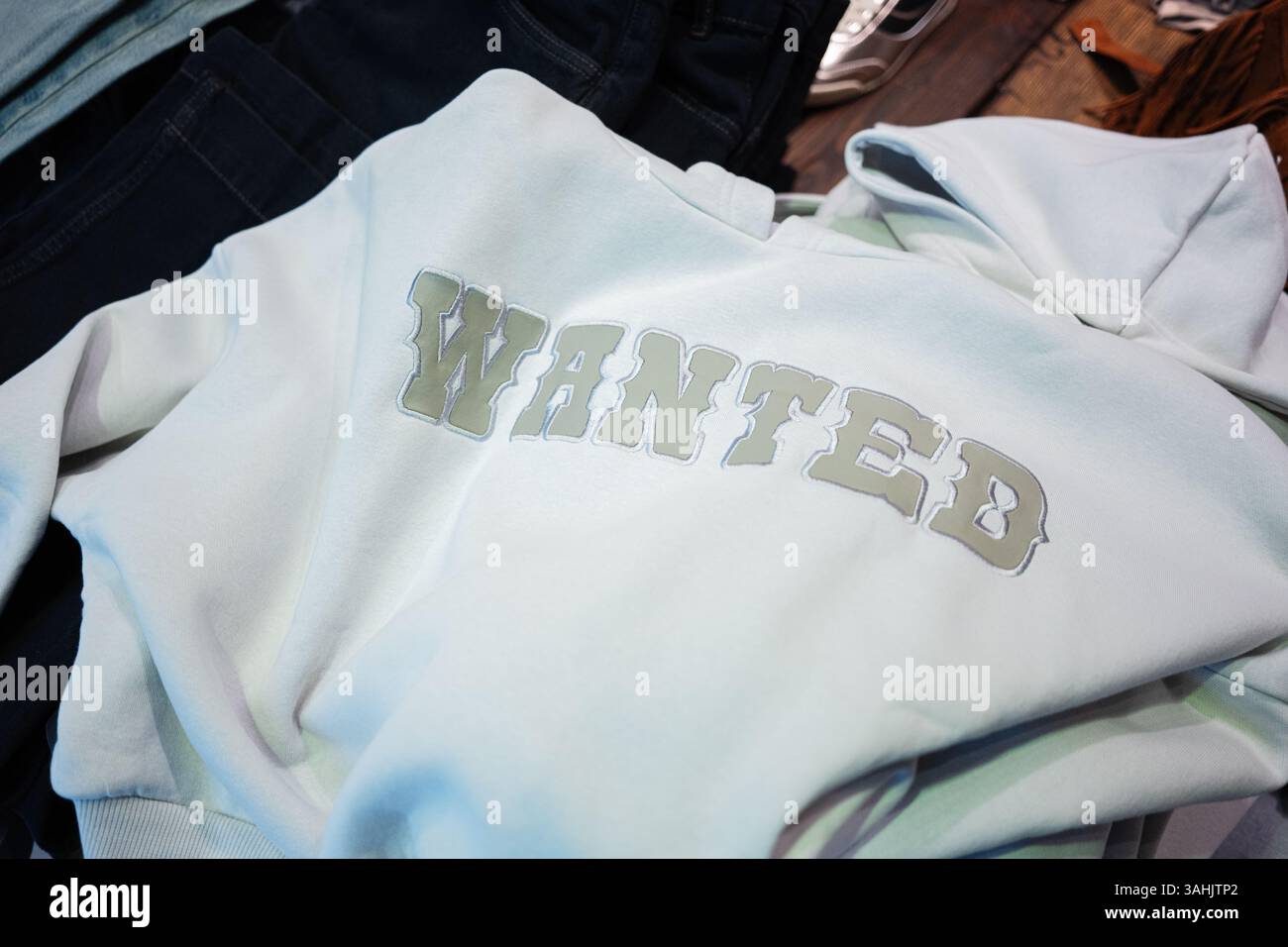 Ein heller Hoodie mit auffälliger Typografie, der auf einer flachen Oberfläche liegen soll Stockfoto