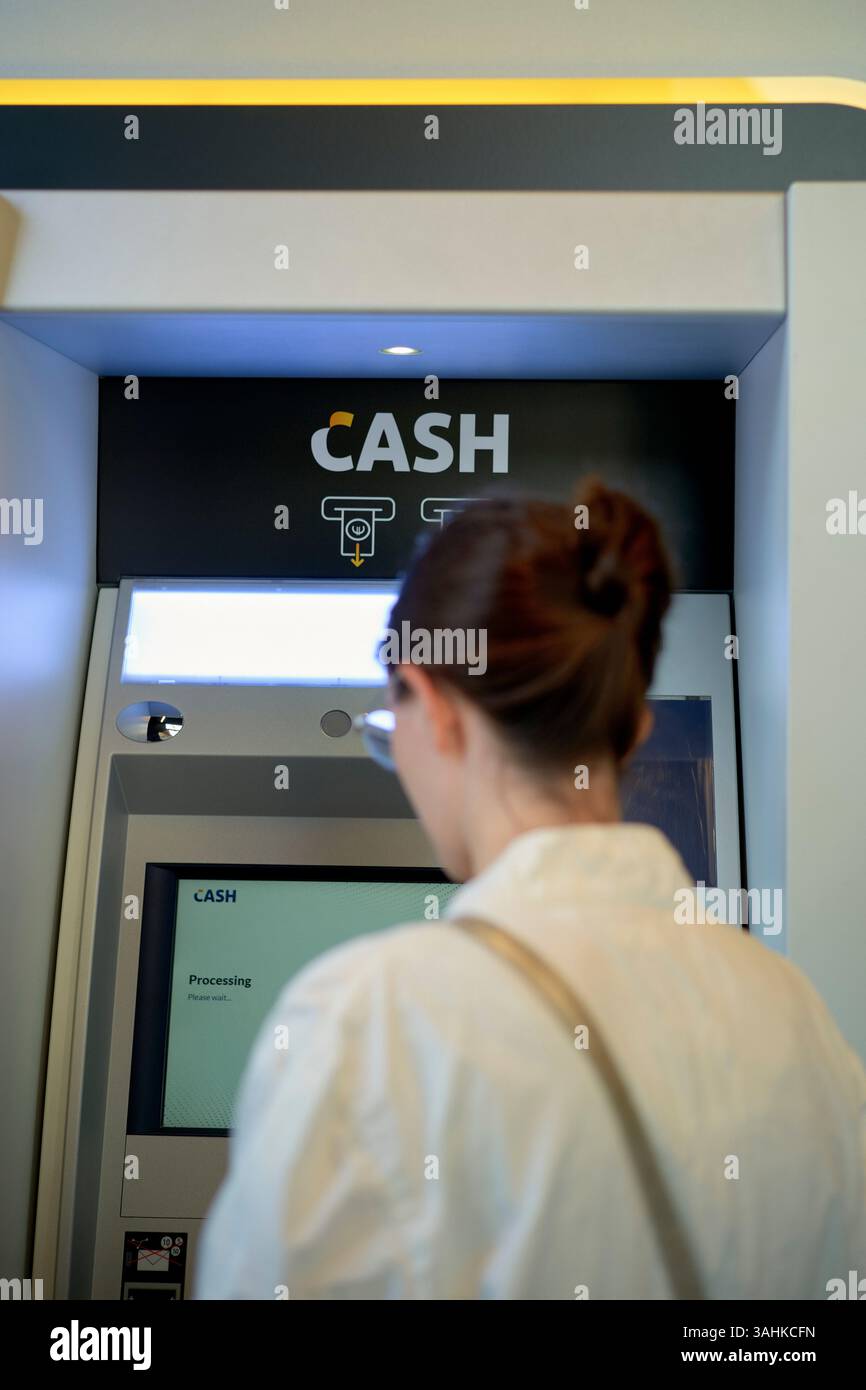 Frau, die einen Geldautomaten in einer modernen Bankumgebung benutzt. Brüssel, Belgien Stockfoto