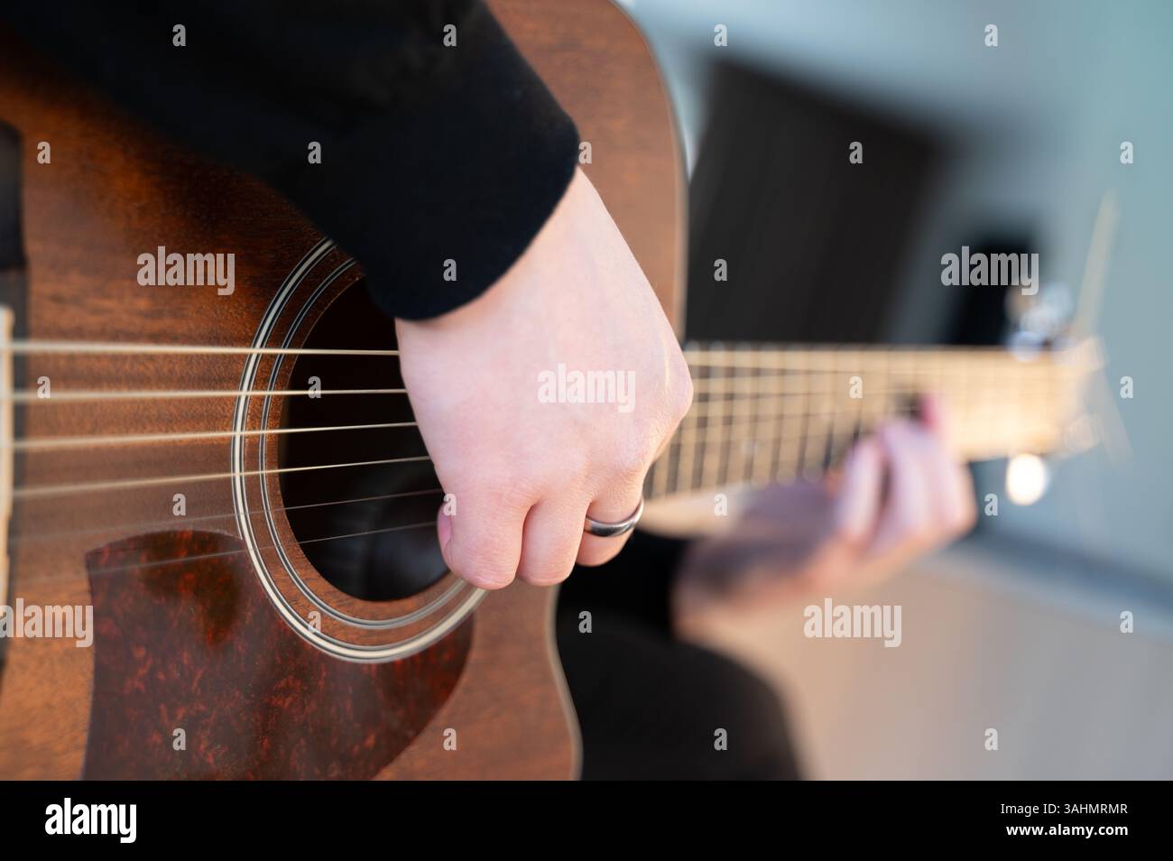 Eine detaillierte Nahaufnahme einer leidenschaftlichen Person, die eine Akustikgitarre spielt und ihre Kunstfertigkeit und ihr musikalisches Talent hervorhebt Stockfoto