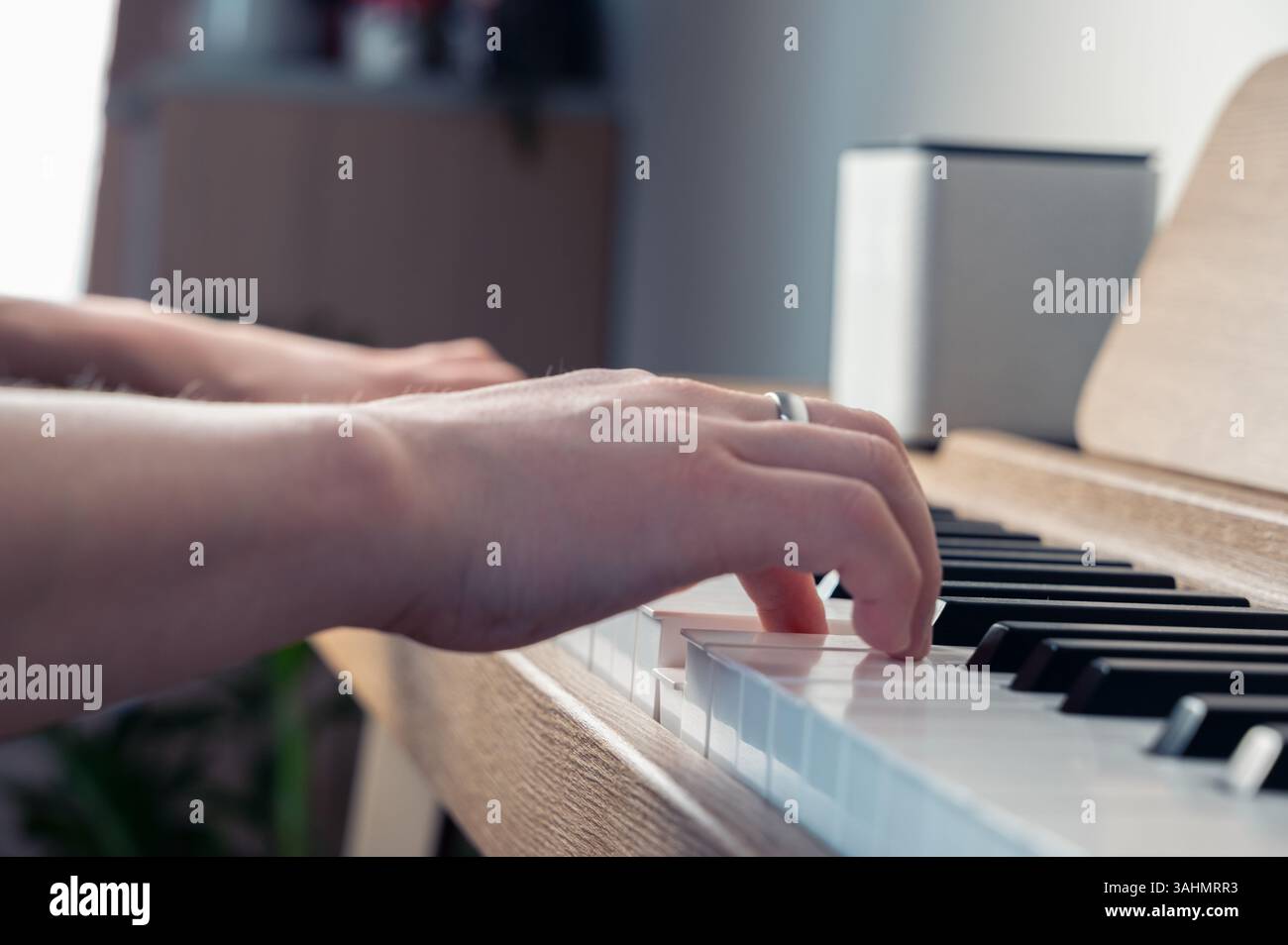 Eine Person spielt geschickt Klavier, trägt einen Ring an einem Finger und zeigt ihr musikalisches Talent und ihren Stil Stockfoto