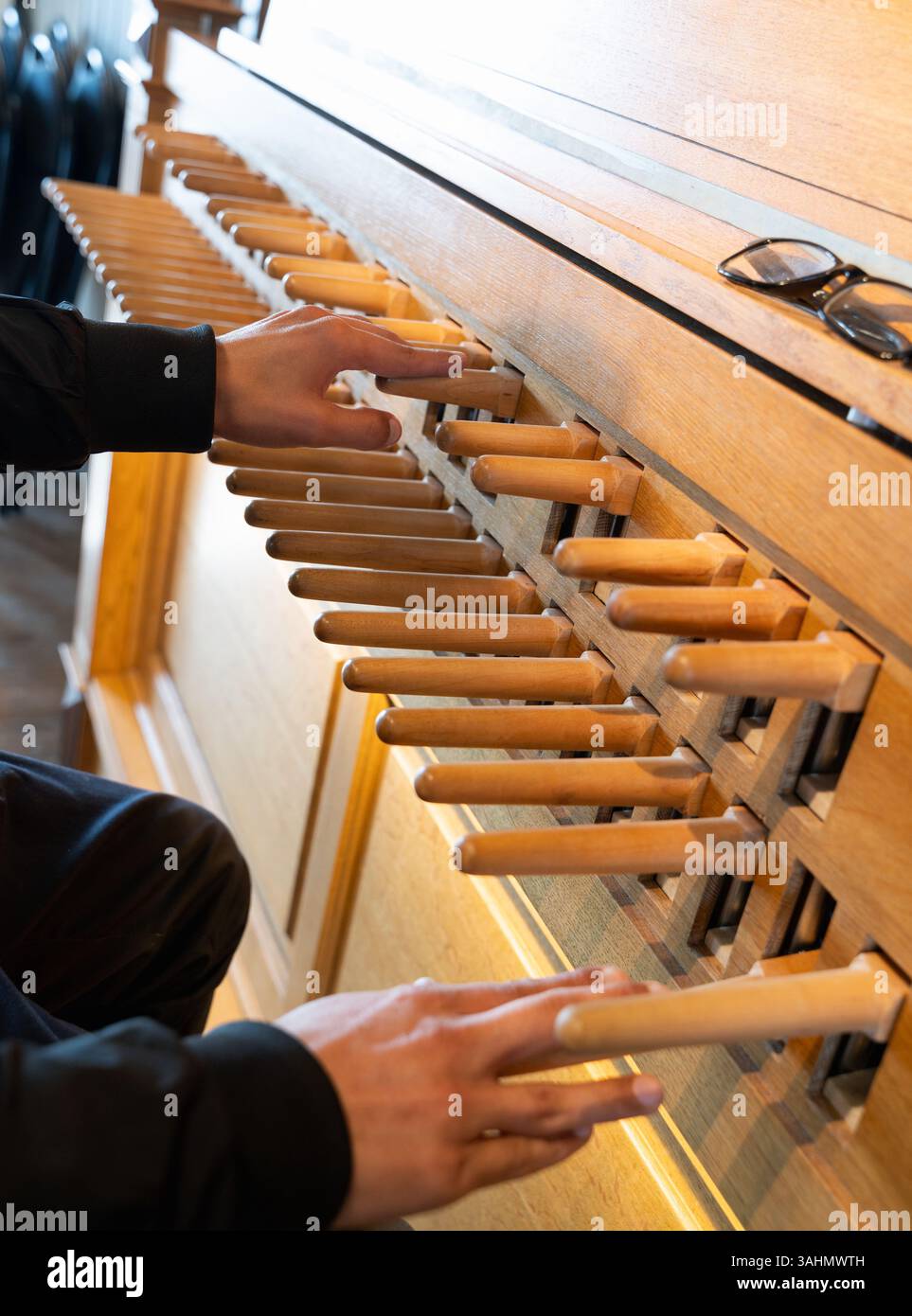 Bei einer Nahaufnahme werden die Hände beim Spielen eines wunderschön gearbeiteten hölzernen Musikinstruments Carillon mit mehreren Ziehungen hervorgehoben Stockfoto