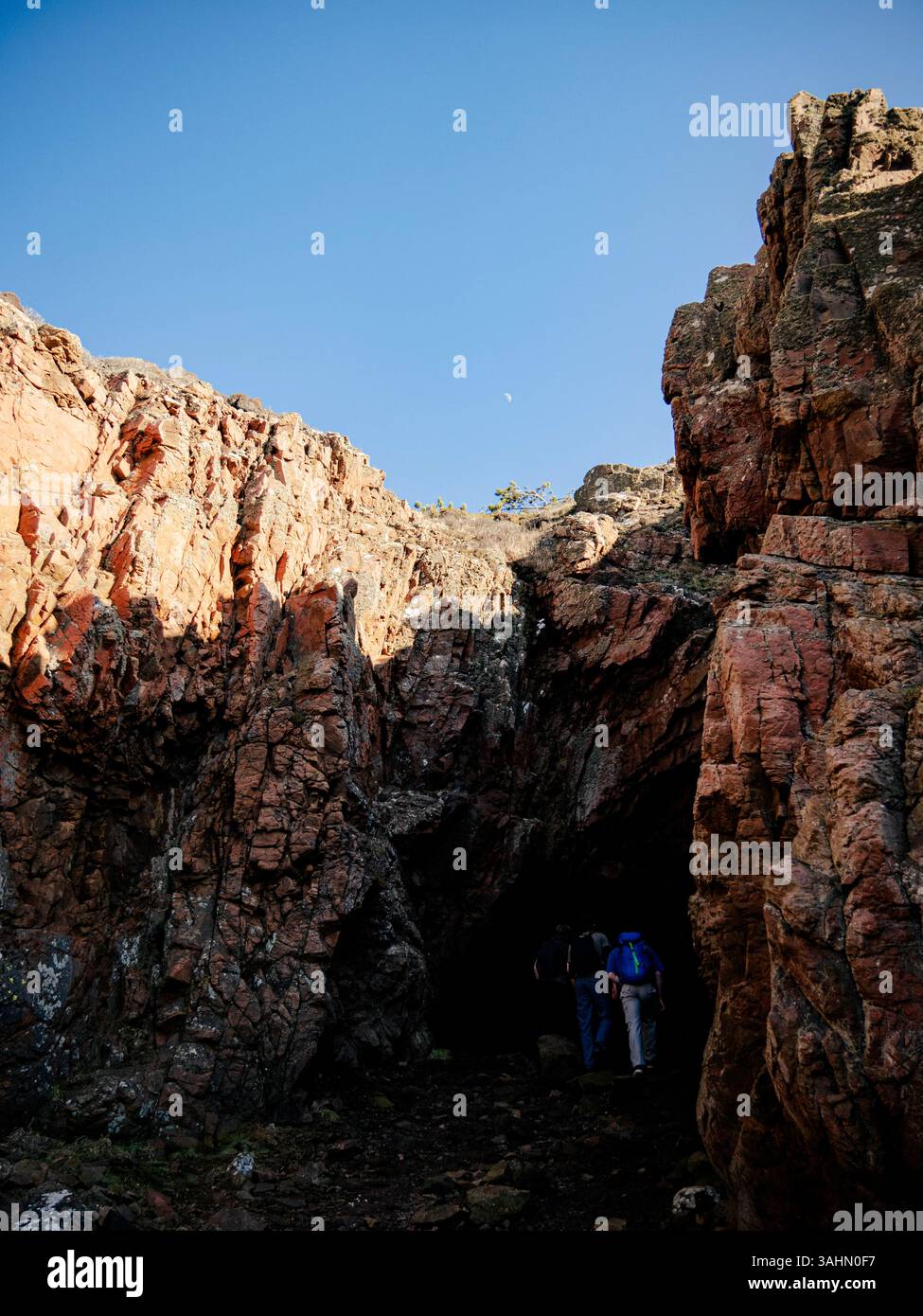 Eine Gruppe von drei abenteuerlustigen Jungs erkundet eine geheimnisvolle Höhle auf Kullaberg, einer zerklüfteten Halbinsel in Schweden. Stockfoto
