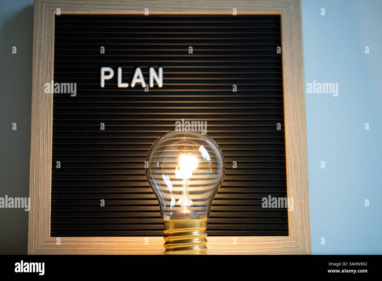 Glühbirne vor der Brieftafel mit der Aufschrift „PLAN“, die Ideen, Kreativität und Strategie für Business, Coaching oder persönliches Wachstum symbolisiert Stockfoto
