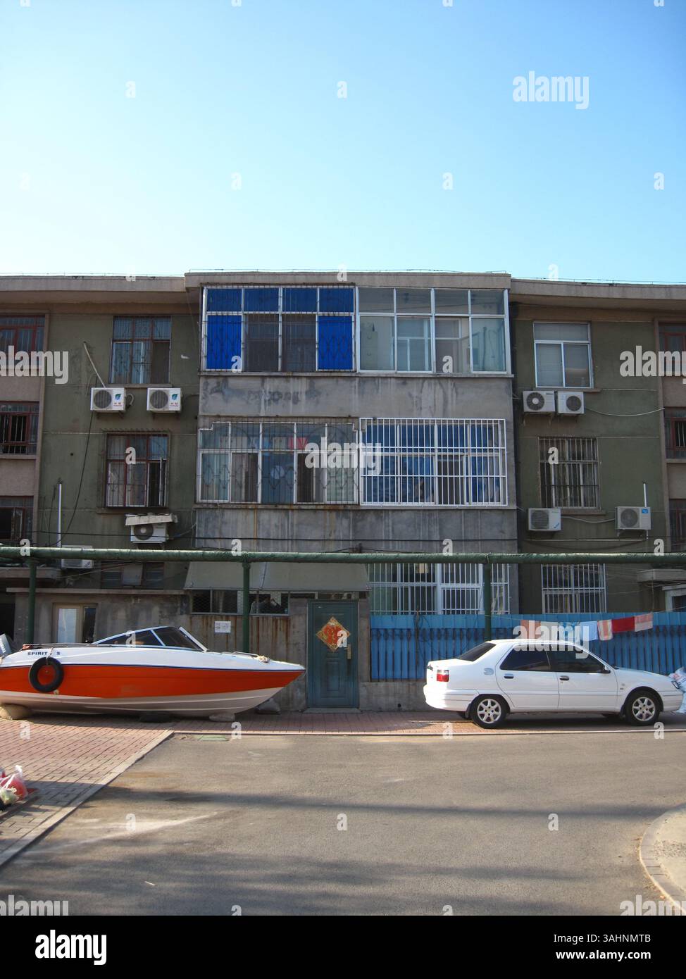 Wohnszene in Dongying, Shandong, China: Citroen Elysee und Speedboat parken vor dem verwitterten Mid-Rise Apartment Komplex in Victory Oilfield Community in der Nähe von Bohai Bay. 2014 Stockfoto