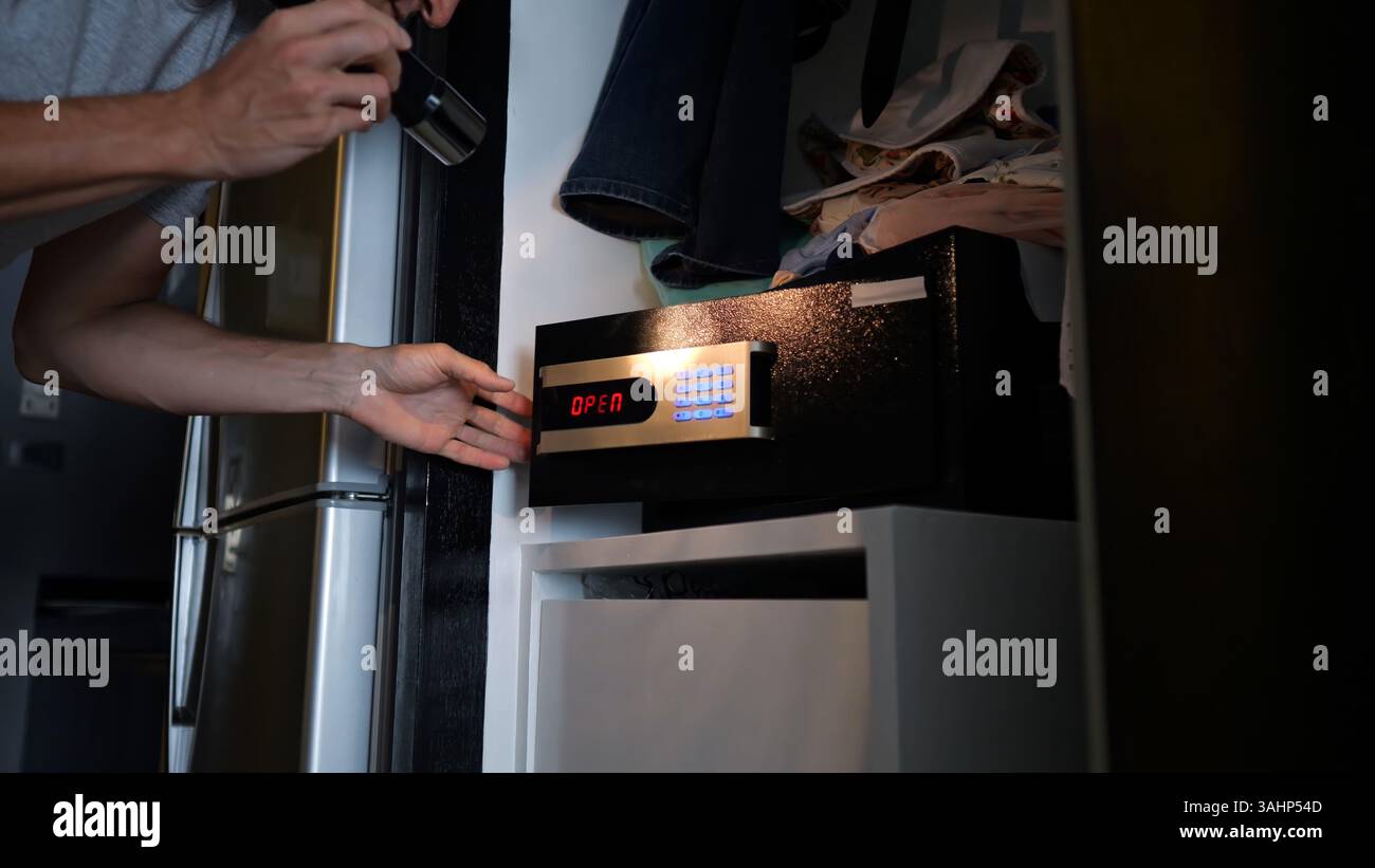 Dieb knackt Hotelsafe mit Taschenlampe Stockfoto