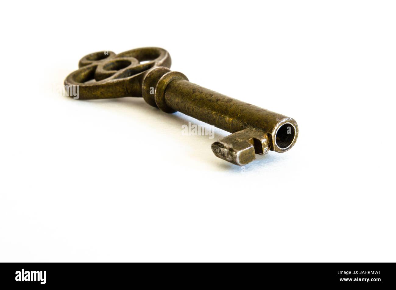 Antiker Skelett-Schlüssel aus Messing auf weißem Hintergrund, in einem Winkel mit Makronaht dargestellt Stockfoto