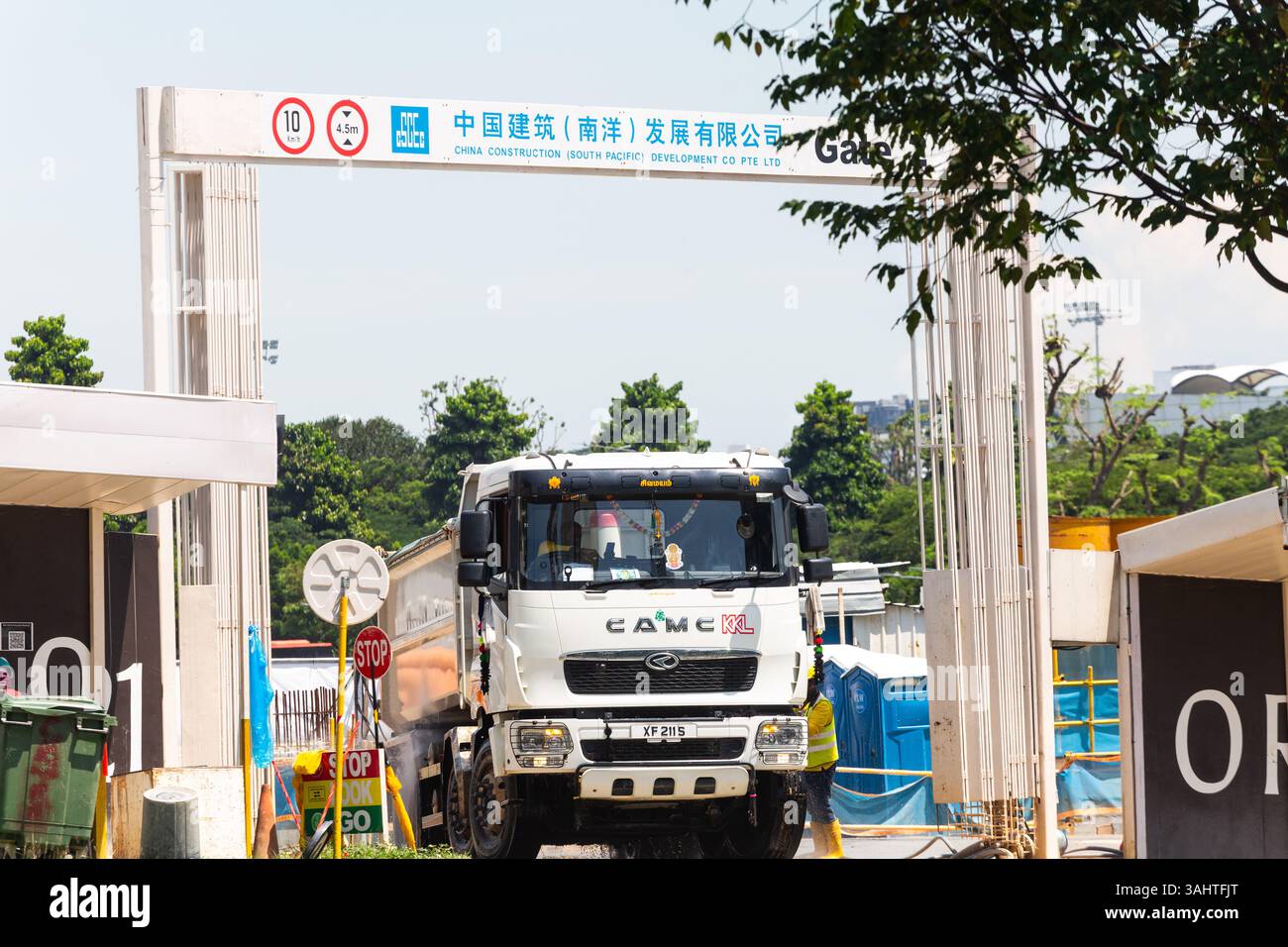 Ein schwerer Sandwagen hielt an der Reinigungsbucht an, um schlammige Reifen vom Wanderarbeiter waschen zu lassen, bevor er die Baustelle verließ. Singapur. Stockfoto
