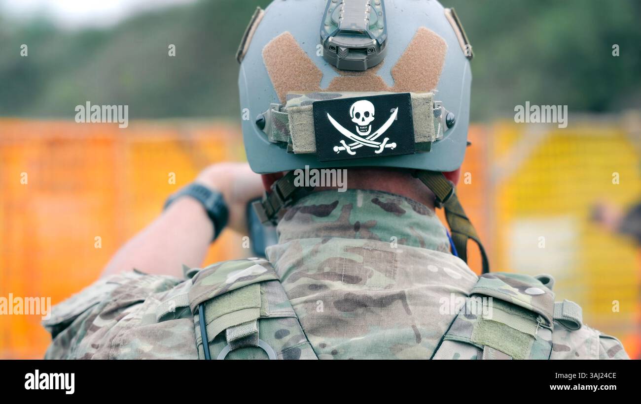 Soldat mit taktischem Helm und Schädelaufnäher. Ein Soldat in Tarnkleidung, der einen taktischen Helm mit Schädel und Kreuzknochen während einer trägt Stockfoto