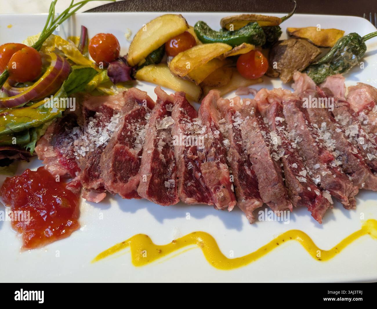 Ungekochtes Steak auf einem Teller mit Gemüse Stockfoto