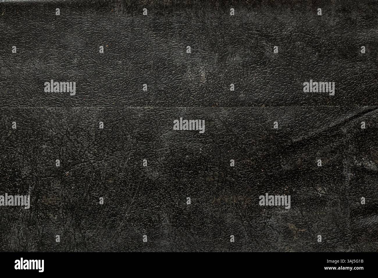 Hintergrund aus schwarzem, altem Leder in Nahaufnahme, das Leder ist körnig, staubig und schmutzig Stockfoto