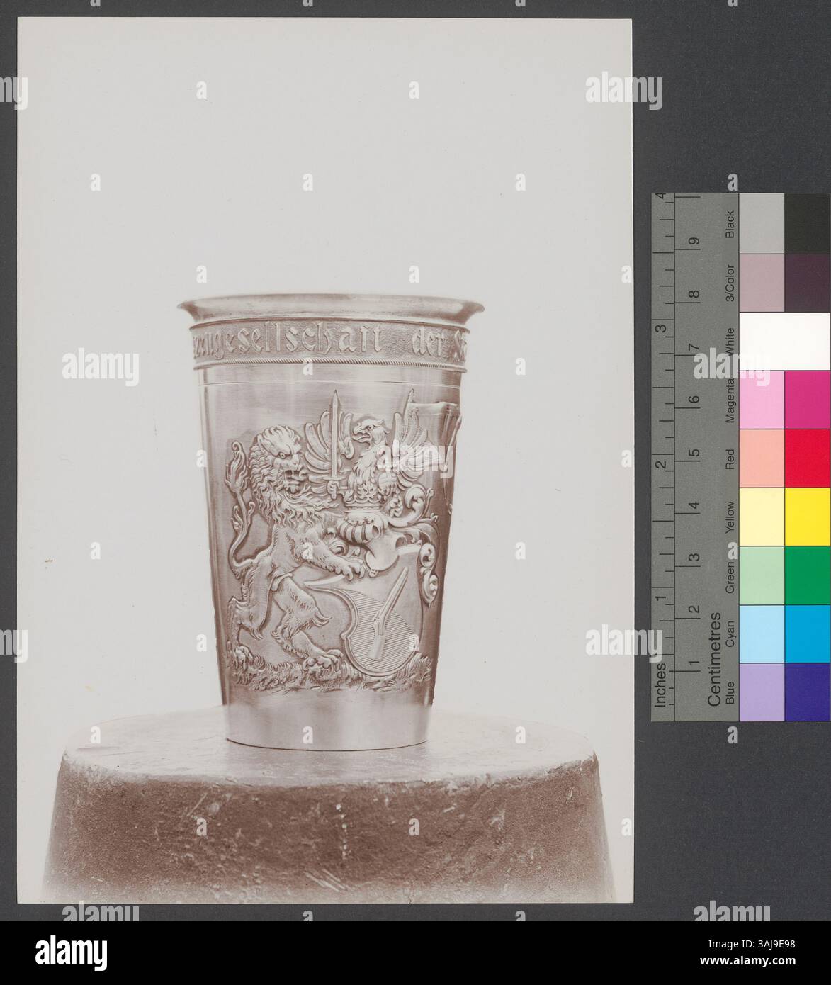 Diese Fotografie von Robert Breitinger aus dem Jahr 1902 zeigt einen Trinkbecher aus Metall mit einer Inschrift für die Zürcher Schützengesellschaft, verziert mit dem Zürcher Banner, einem Gewehr, einem Löwen und einem Kaiseradler mit Schwert und Kugel. Stockfoto