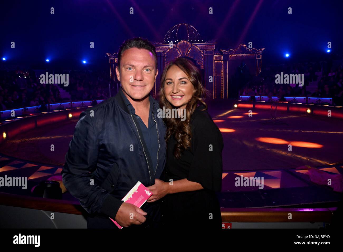 München, Deutschland. April 2025. Sänger Stefan Mross und Eva Luginger stehen vor dem Ring vor der Premiere der Farbenspiel Gold Edition im neuen Zirkuszelt des Circus Krone auf der Theresienwiese. Quelle: Felix Hörhager/dpa/Alamy Live News Stockfoto München, Deutschland. April 2025. Sänger Stefan Mross und Eva Luginger stehen vor dem Ring vor der Premiere der Farbenspiel Gold Edition im neuen Zirkuszelt des Circus Krone auf der Theresienwiese. Quelle: Felix Hörhager/dpa/Alamy Live News Stockfoto