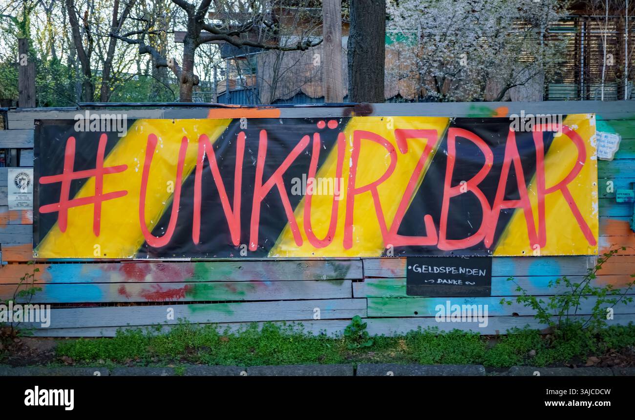 Buntes Banner mit dem Hashtag '#UNKÜRZBAR' auf einem Holzzaun im Berliner Stadtteil Prenzlauer Berg, Teil einer Protestaktion oder einer sozialen Initiative. Stockfoto