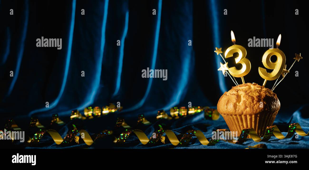 Nummer 39 goldene Festkerze und kleine Sterne in süßem Cupcake auf hellblauem Samthintergrund. Konzept der Feier von Geburtstag, Jubiläum Stockfoto