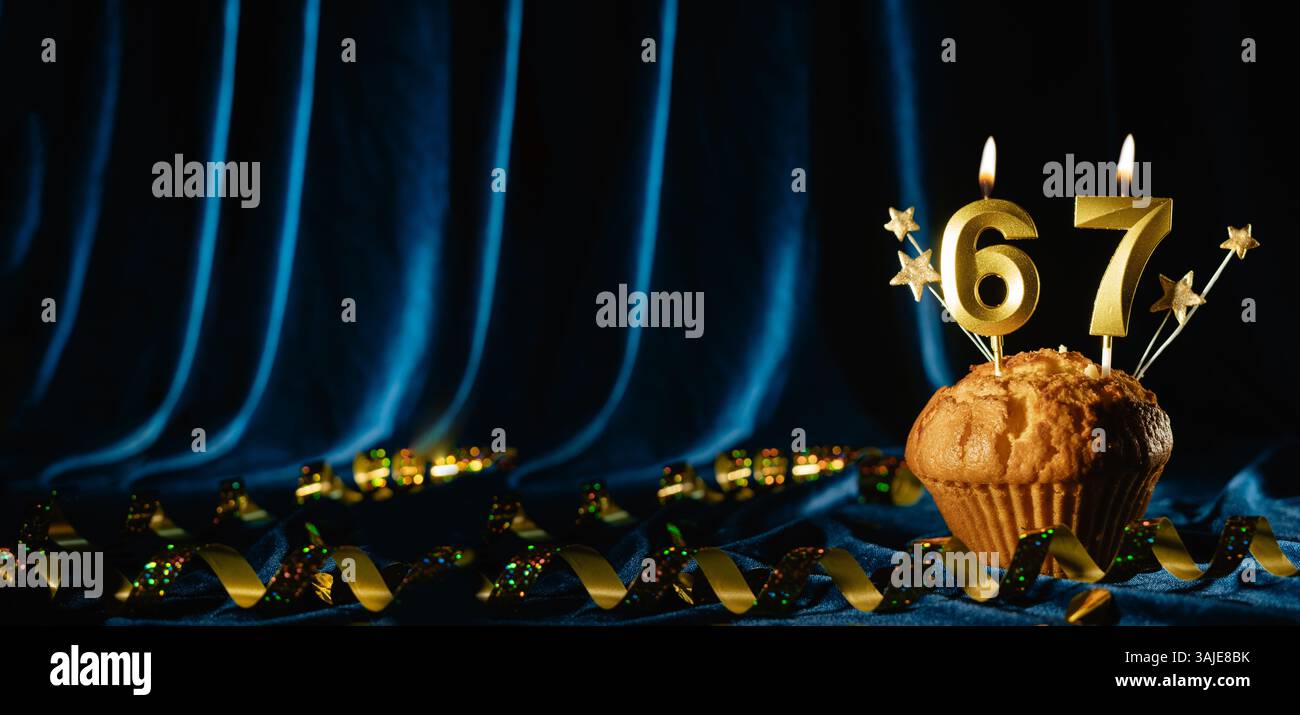 Nummer 67 goldene Festkerze und kleine Sterne in süßem Cupcake auf hellblauem Samthintergrund. Konzept der Feier von Geburtstag, Jubiläum Stockfoto