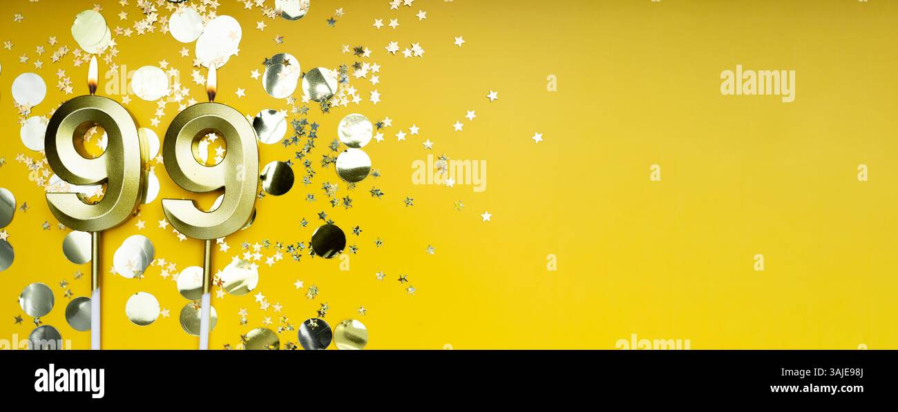 Neunundneunzig Jahre Geburtstag. Nummer 99 goldene Festkerze. Gelber festlicher Hintergrund. Konzept der Geburtstagsfeier oder Jubiläumsfeier. Banner. Stockfoto