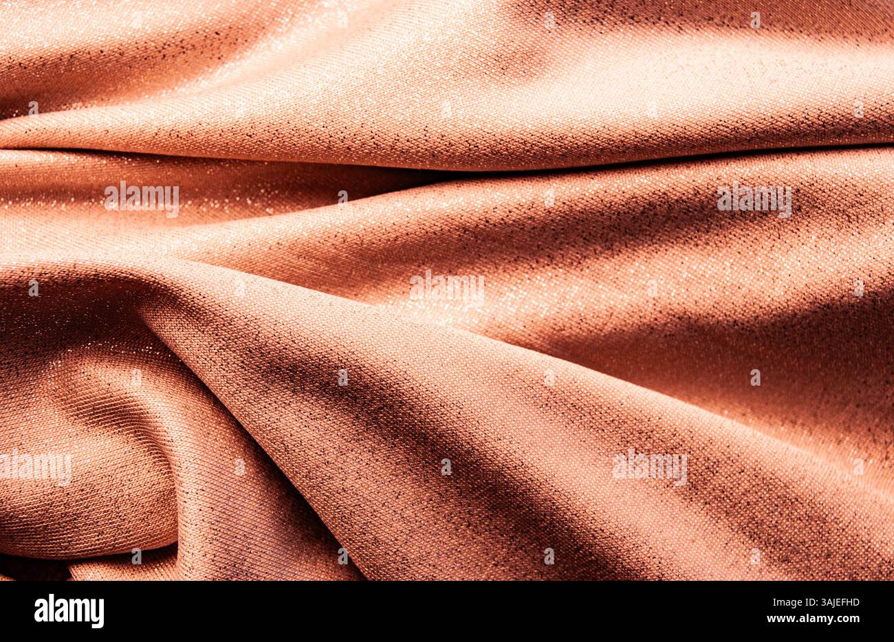 Glatter, orangefarbener Seidenstoff in Pastellfarben mit sanftem Glanz und weichen fließenden Falten für einen warmen und eleganten Hintergrund. Stockfoto