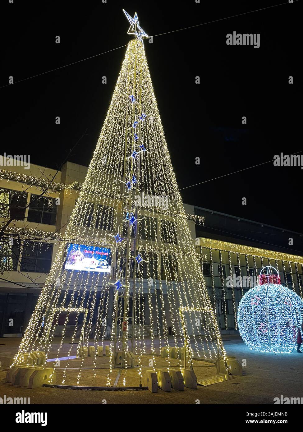 Hell erleuchteter Weihnachtsbaum und Ornamente, die während einer festlichen Feiertagsnächteszene in Madrid, Spanien, festgehalten wurden. Stockfoto