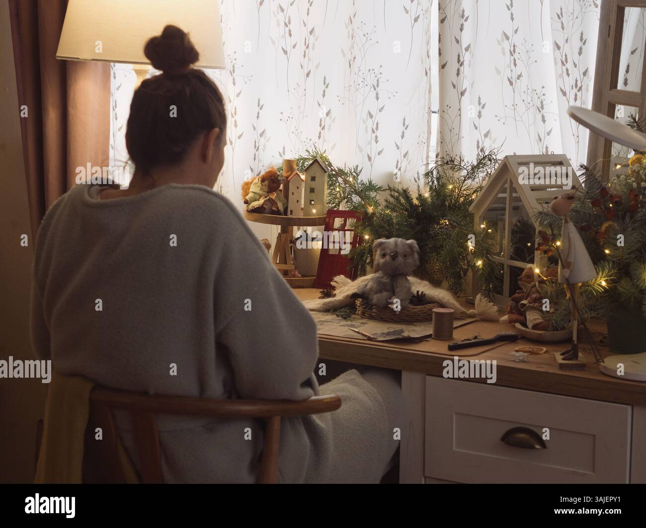 Rückansicht einer Frau, die an einem Schreibtisch mit Weihnachtsdekoration bastelt Stockfoto