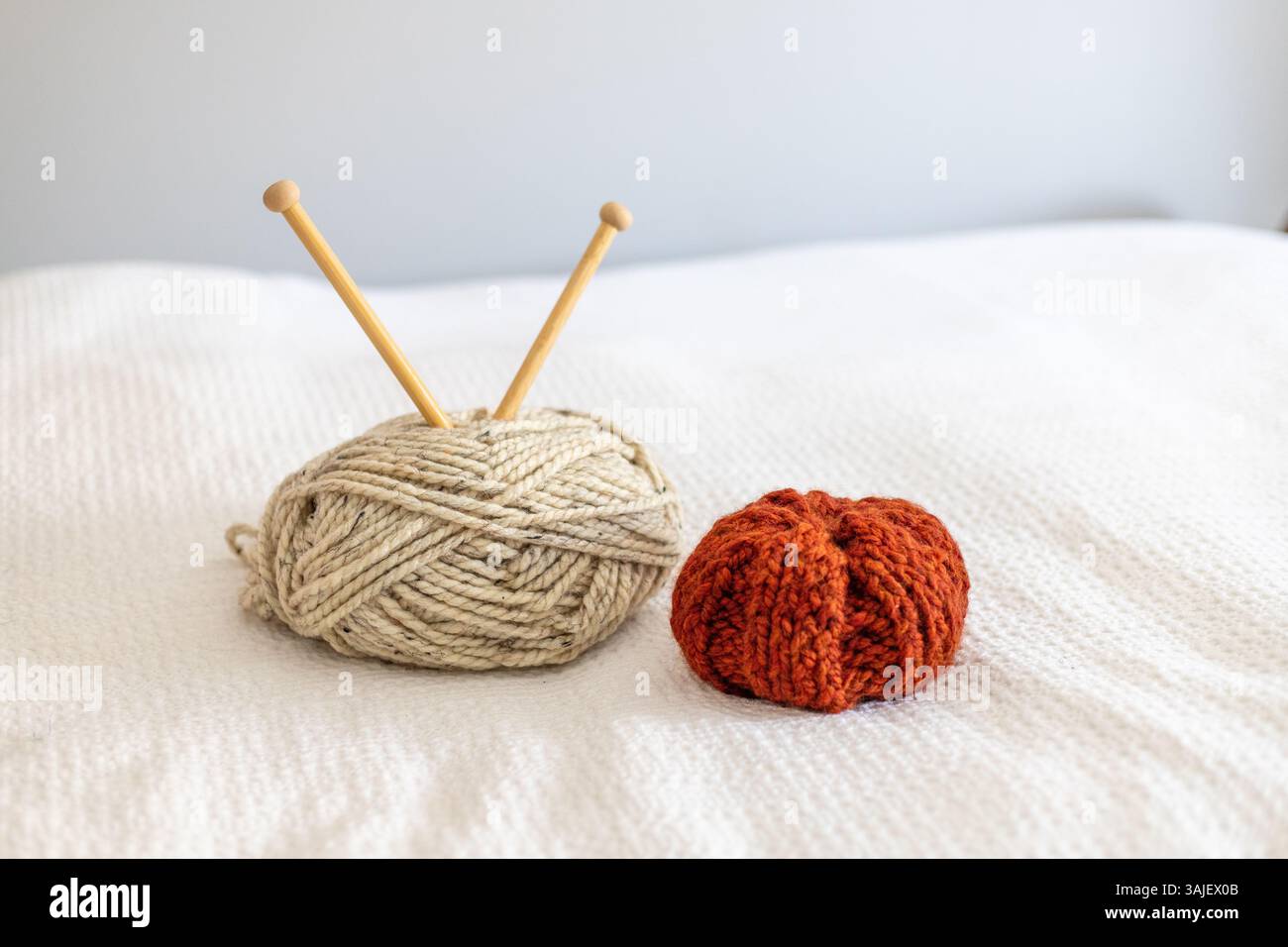 Weißes Garn und ein verbrannter, orange gestrickter Kürbis Stockfoto