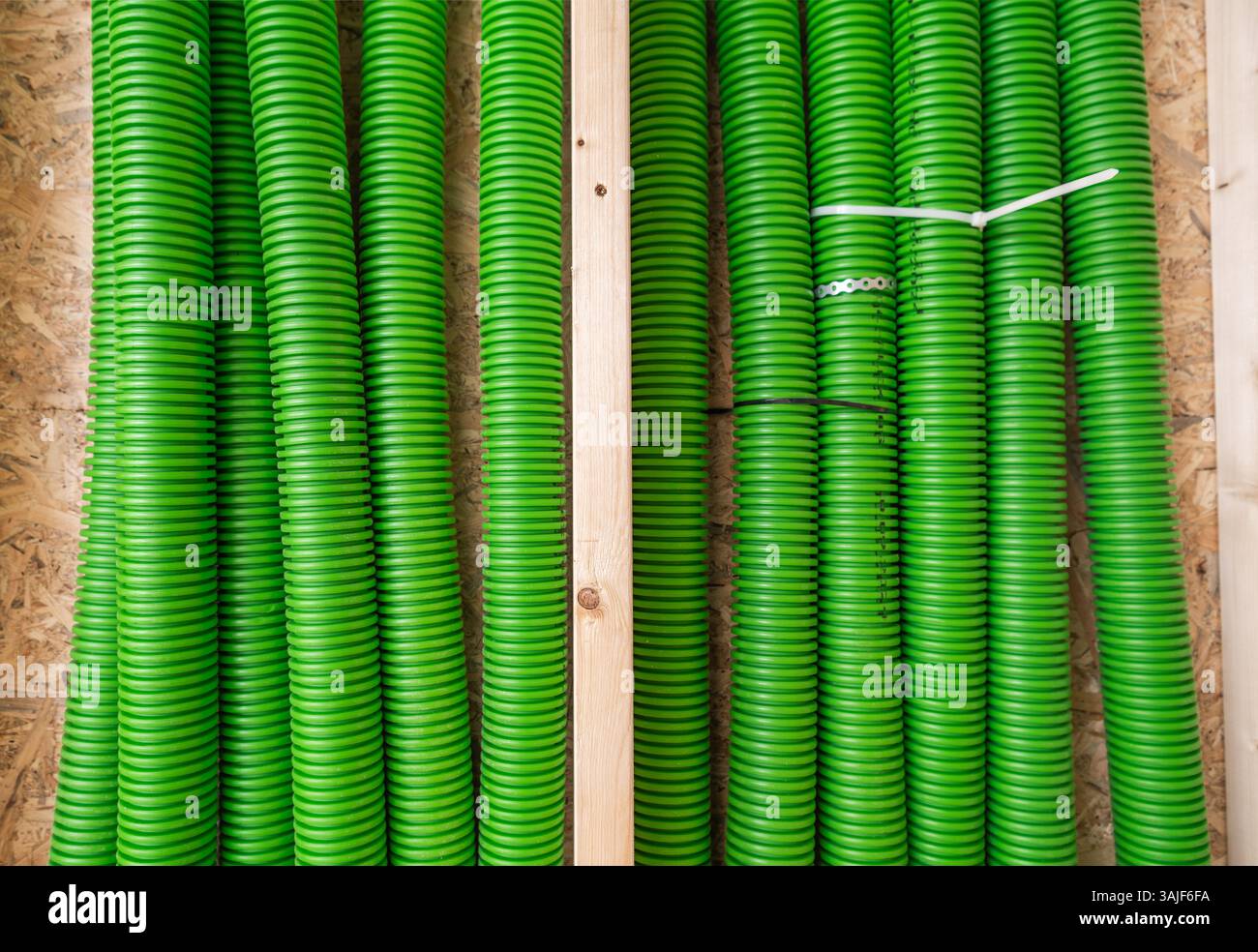 Leuchtend grüne Schläuche sind in einem Lagerbereich auf Holzregalen gestapelt und angeordnet, um eine aufgeräumte Sammlung von Geräten zu präsentieren. Die Einstellung hebt A hervor Stockfoto