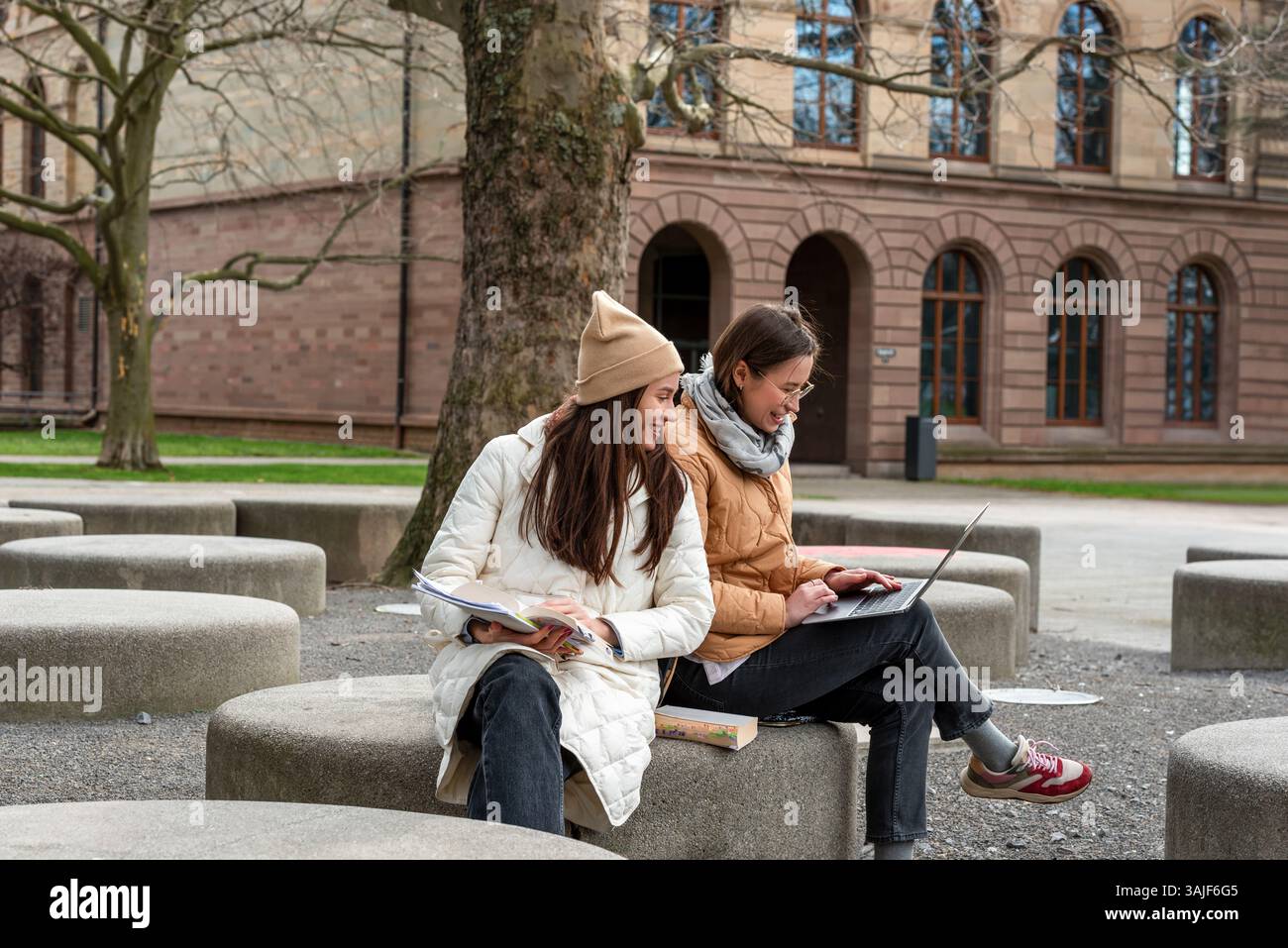 Zwei Studenten lernen im Freien mit Laptops und Büchern in einem malerischen University Park Stockfoto